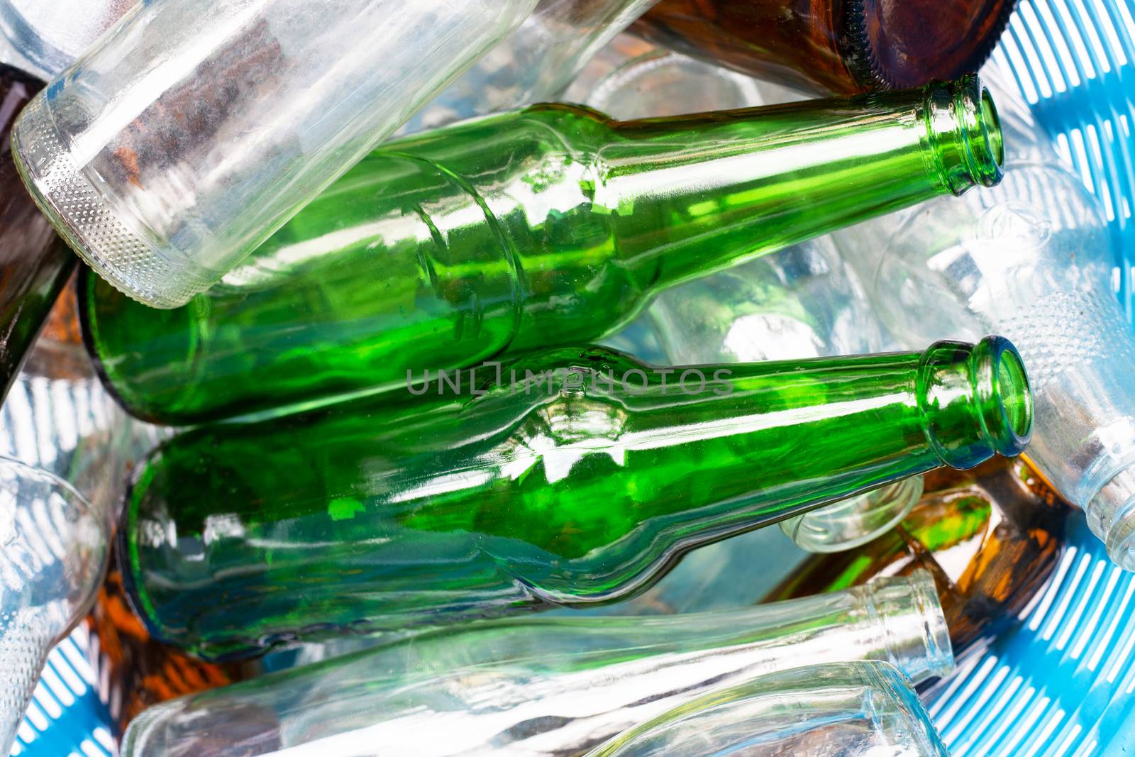 Glass bottles in blue waste basket.