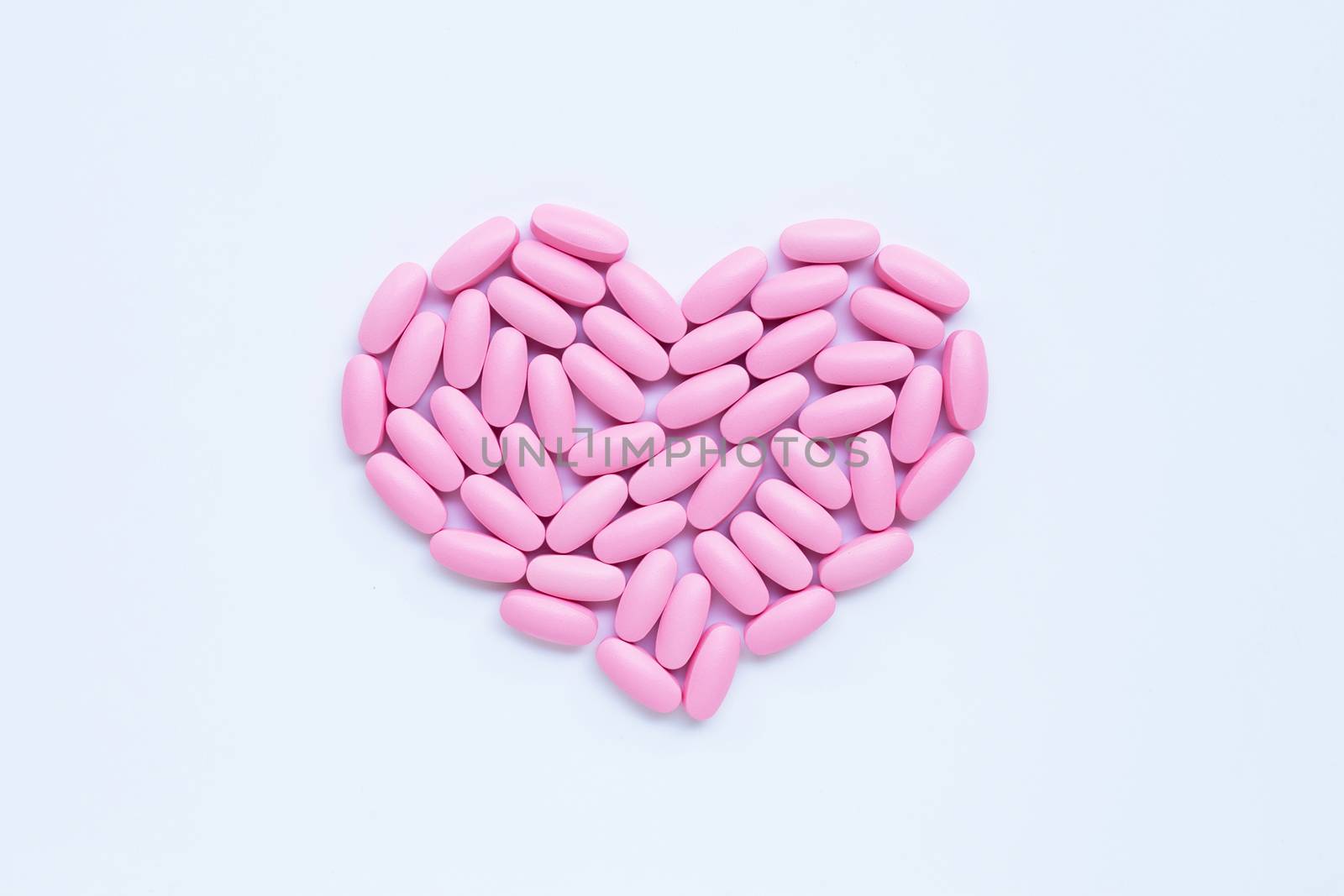 Pink medicine pills on white background. Heart shape