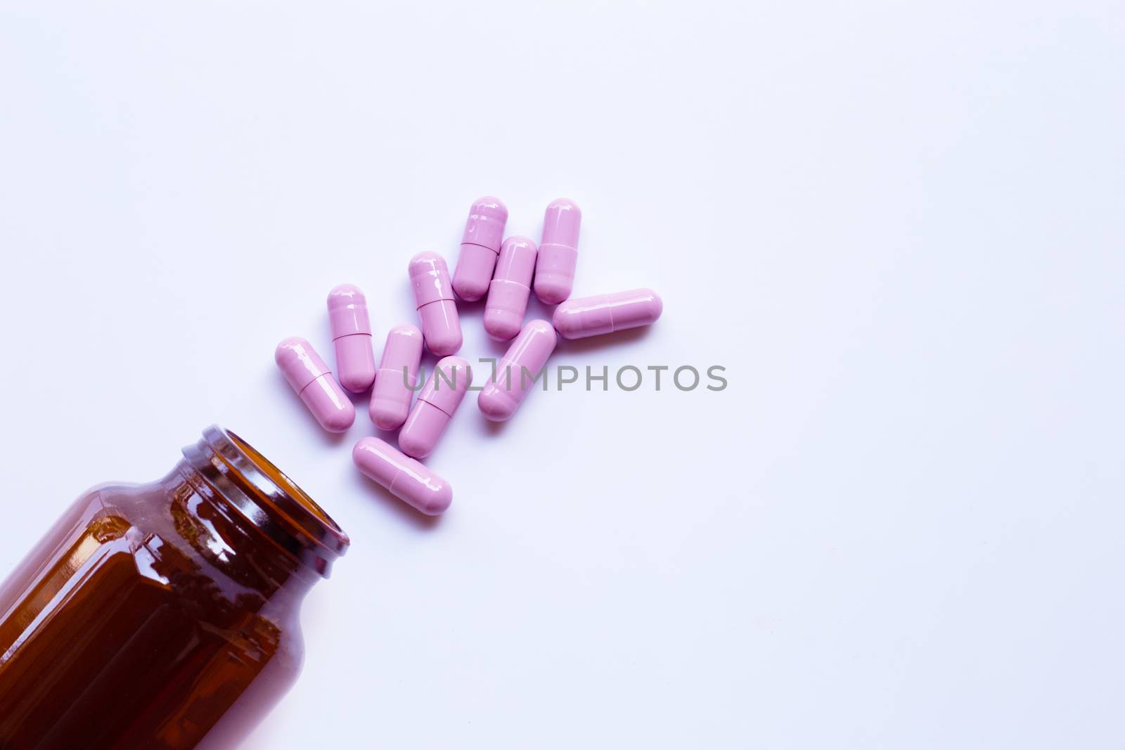 Bottle with purple medicine capsules pills on white
