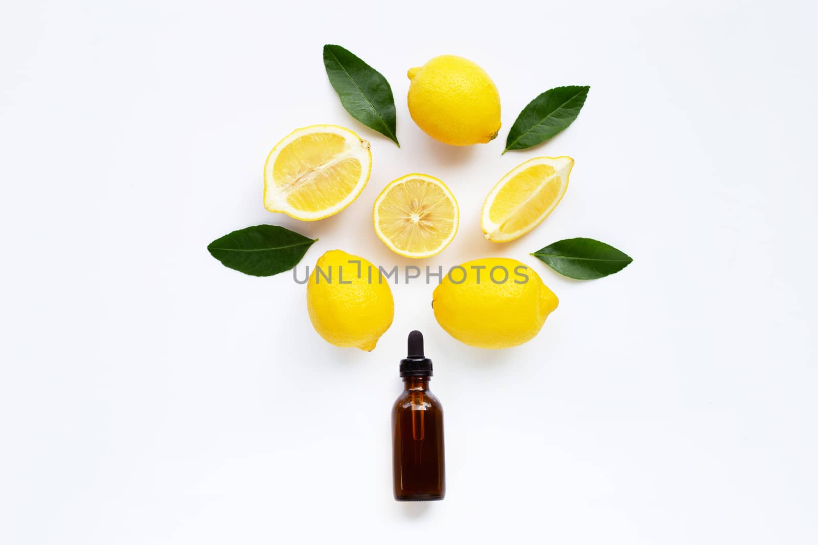 Essential oil with lemon and green leaves isolated on white background.