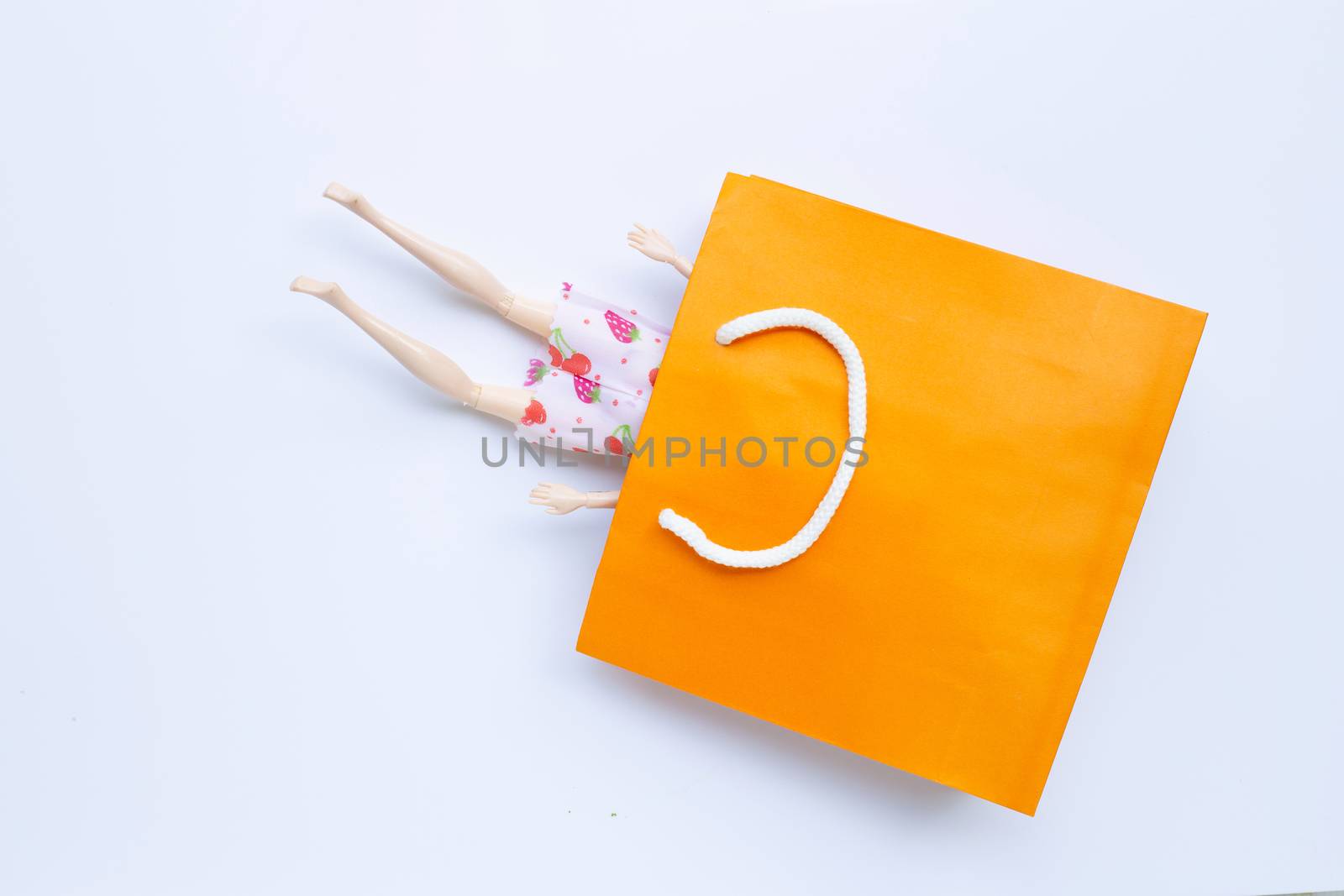 Woman doll  legs with paper shopping bag on white background. Copy space