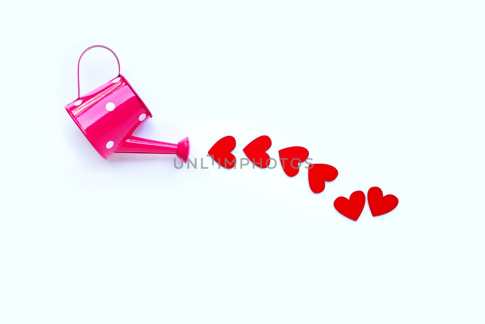 Pink watering can with wooden heart shaped on  white background, Valentines day concept. Copy space