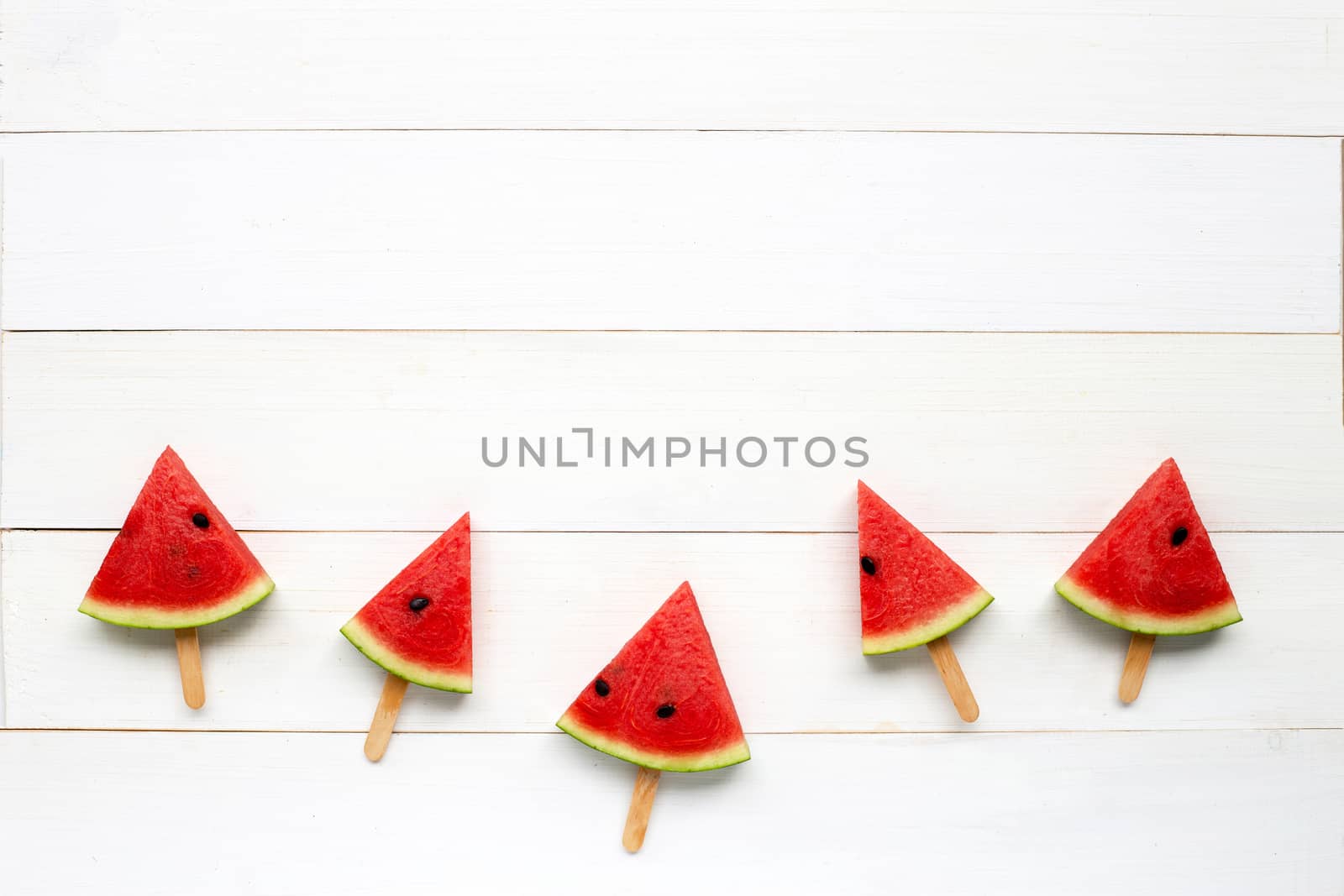Watermelon slice popsicles on white wooden background. Copy space