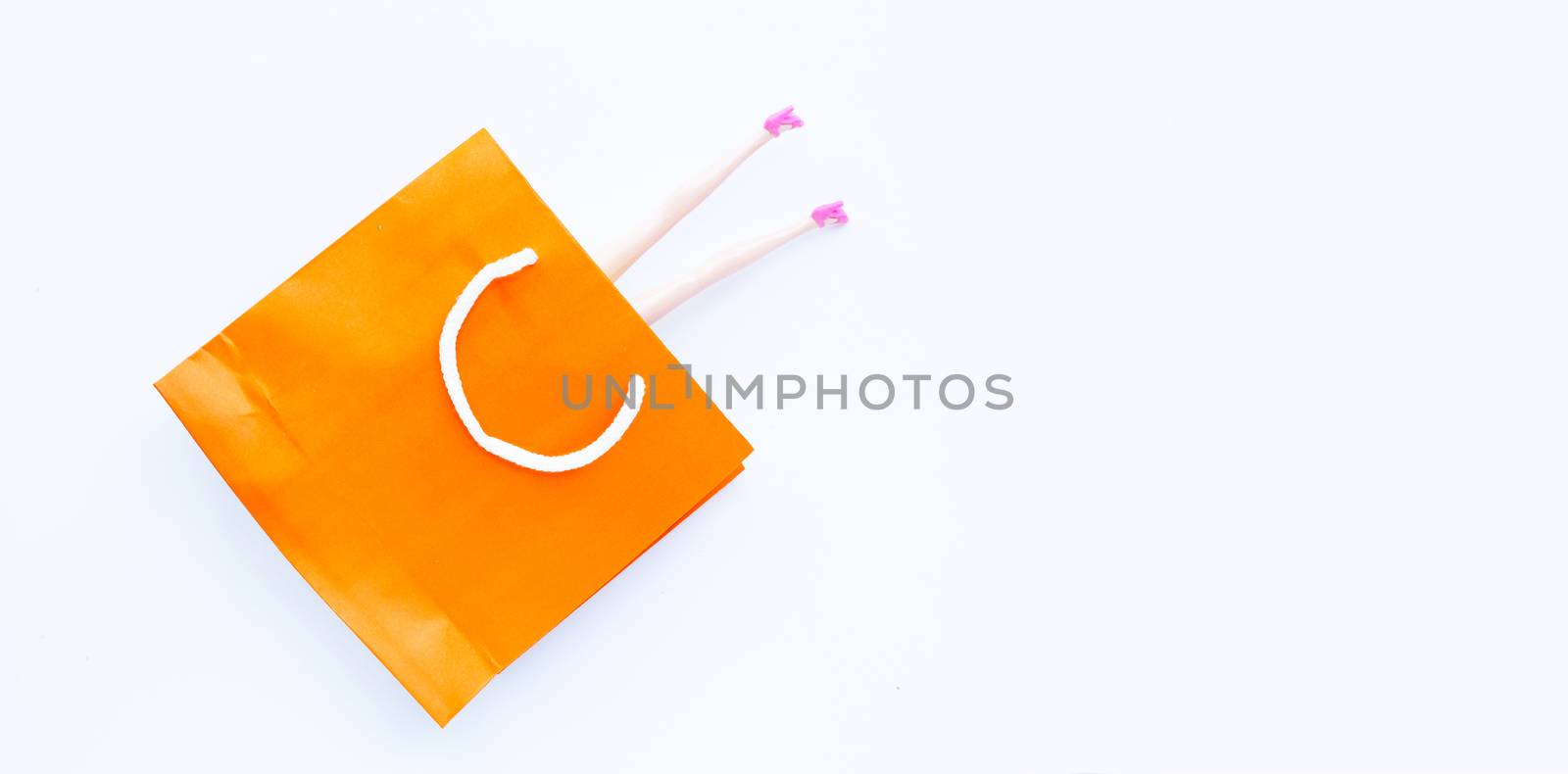Woman doll legs with paper shopping bag on white background. Copy space