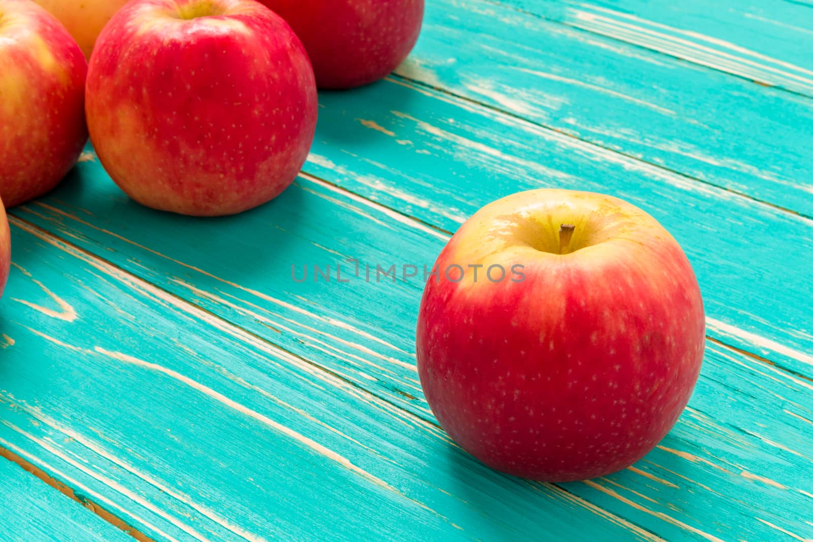Group of red apple on blue wooden background.