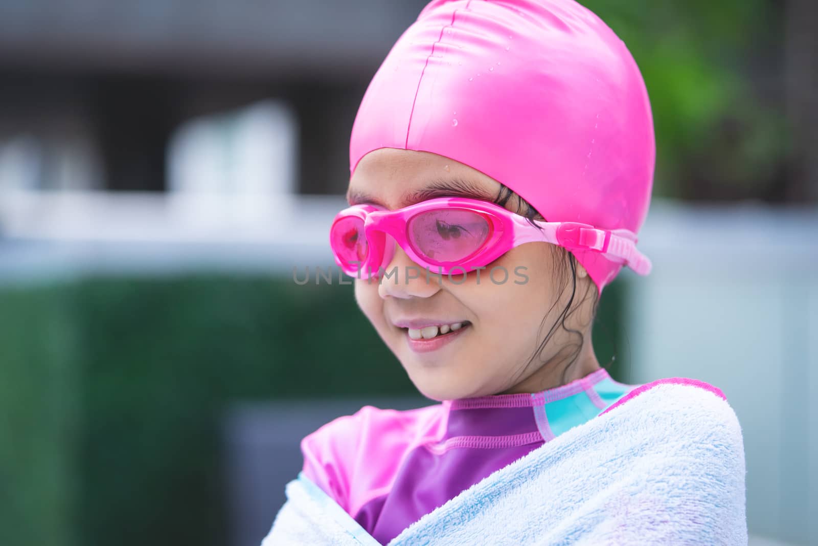 Little asian girl is swimming with glasses and towel
