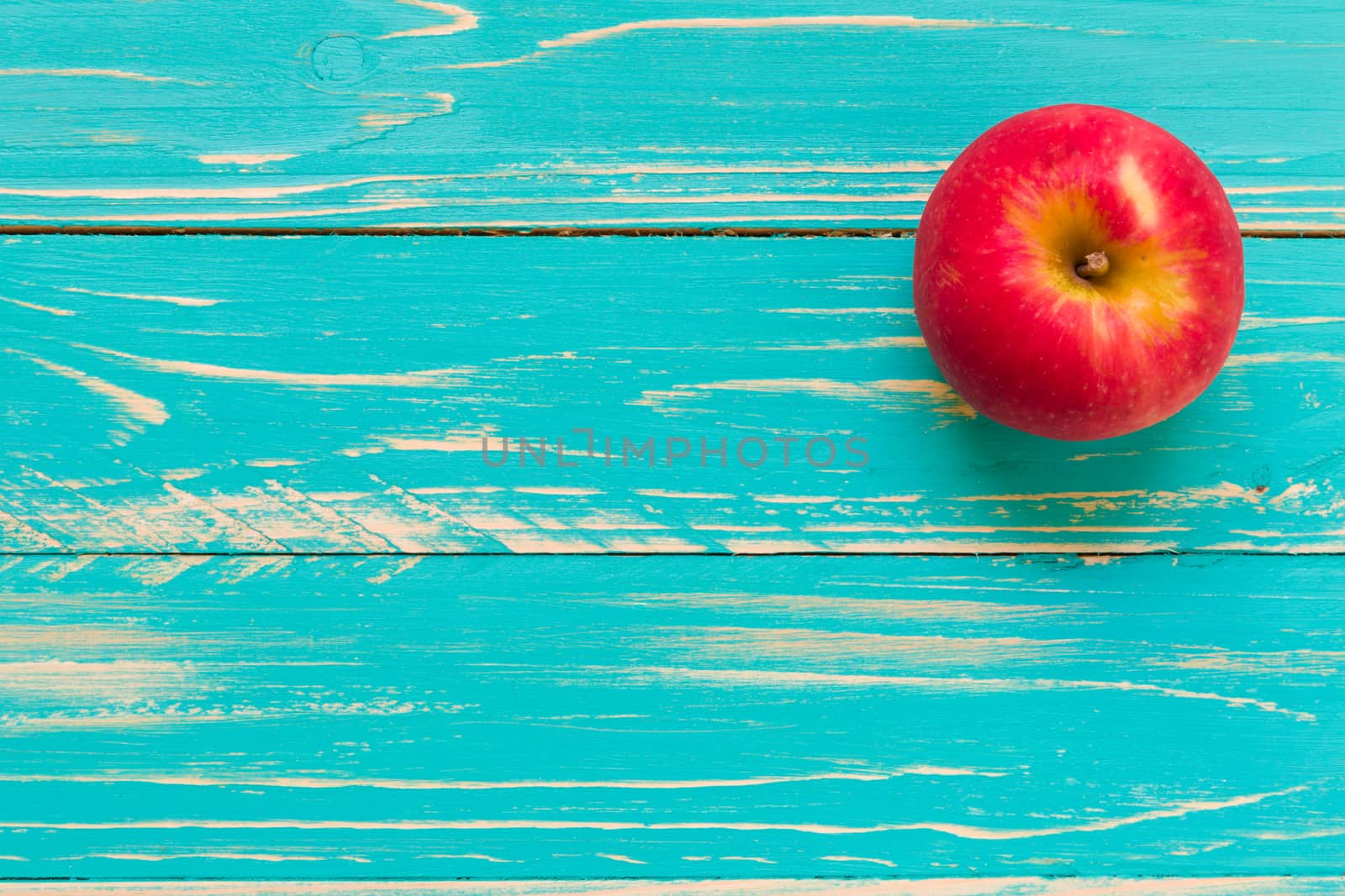 Red apple on vintage blue wooden background.