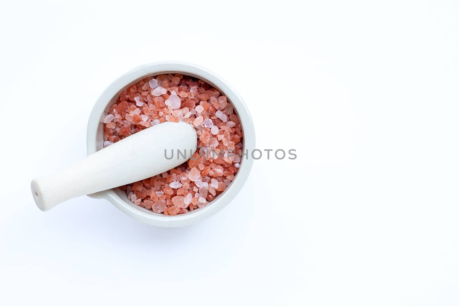 Pink himalayan salt in mortar with pestle on with background. Copy space