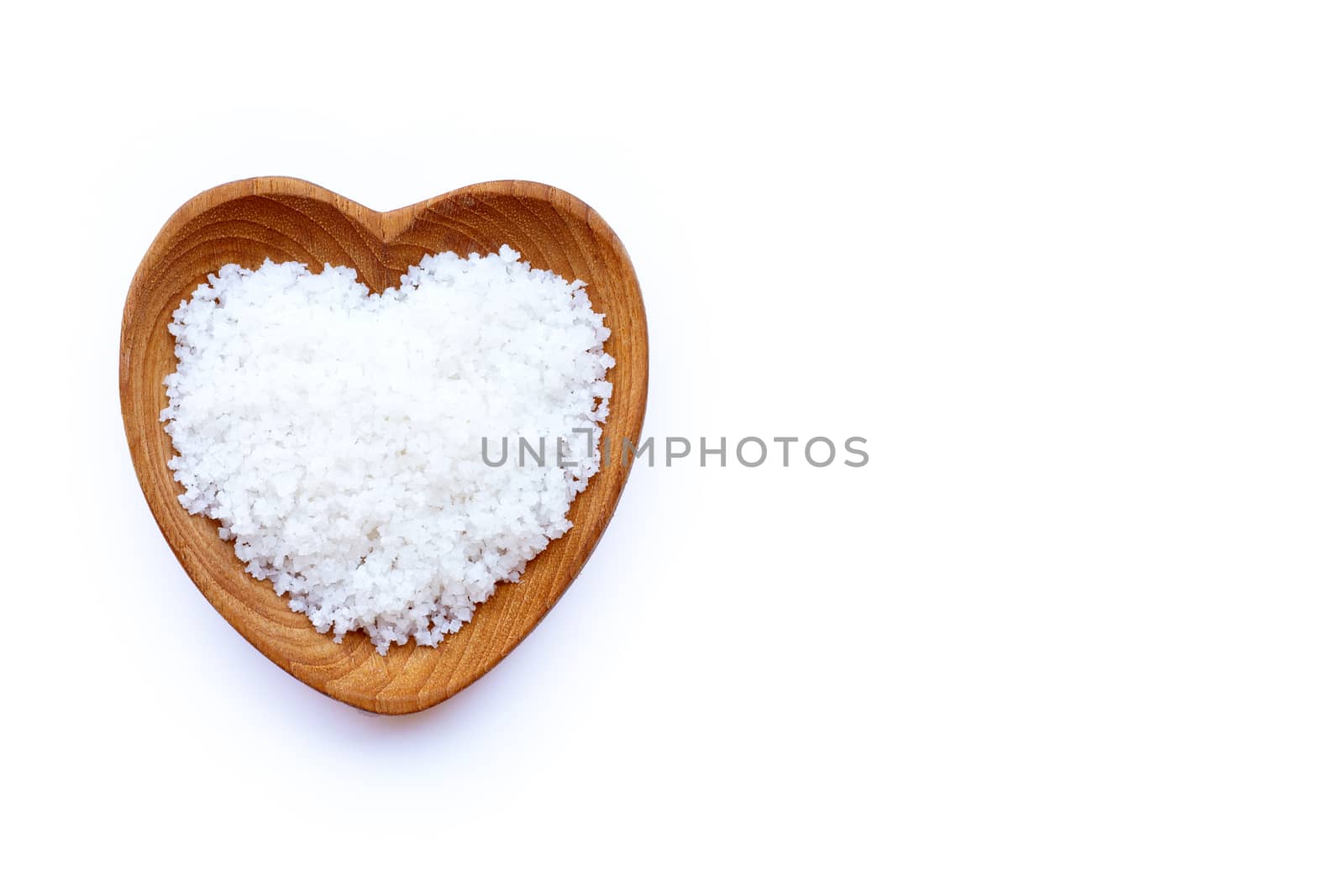 Flower of salt in heart shaped wooden bowl on white background.