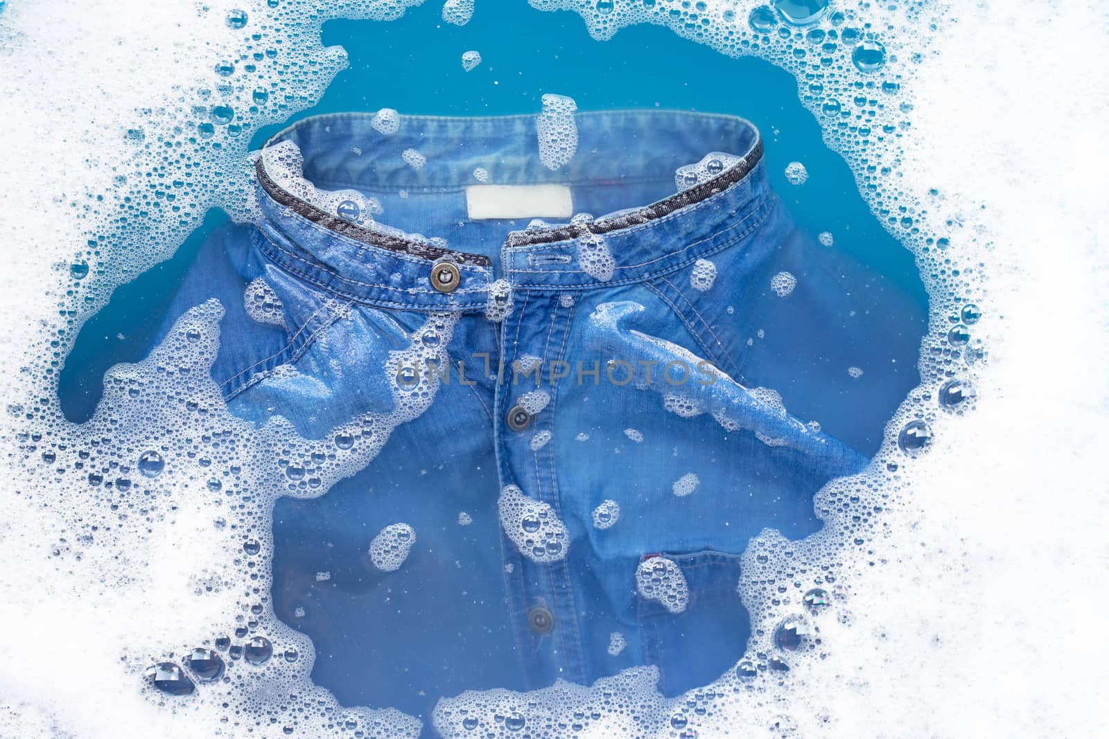 Jean shirt soak in powder detergent water dissolution. Laundry concept