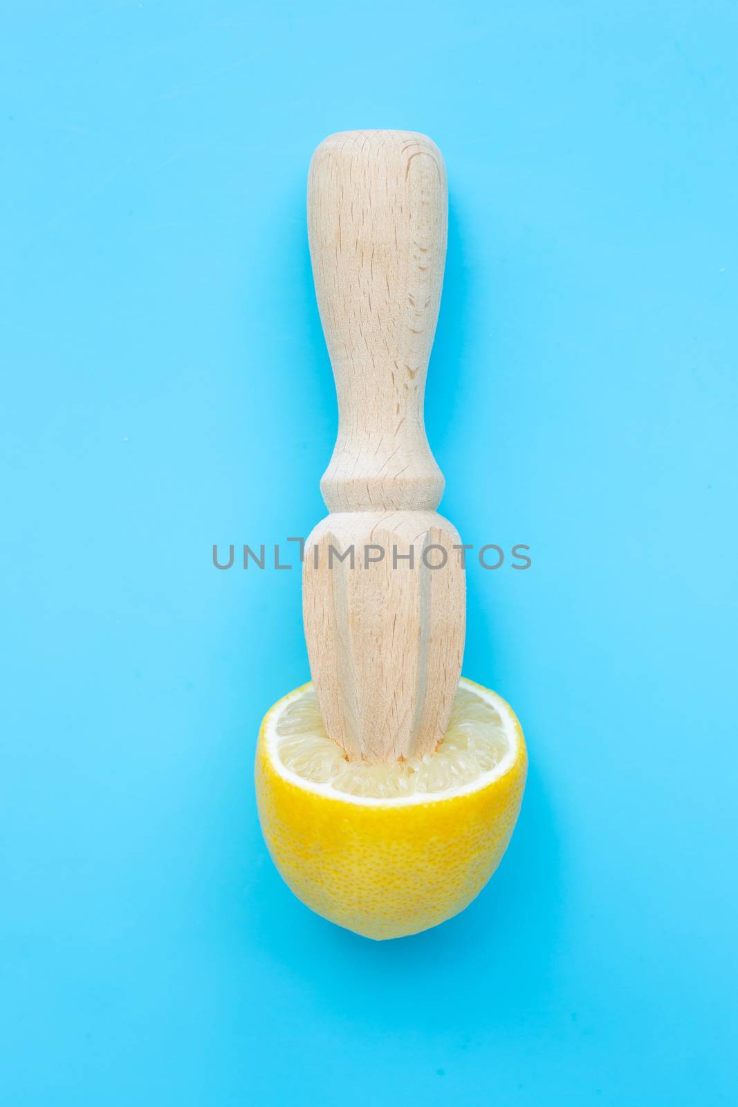 Fresh lemon with wooden juicer on blue background. 