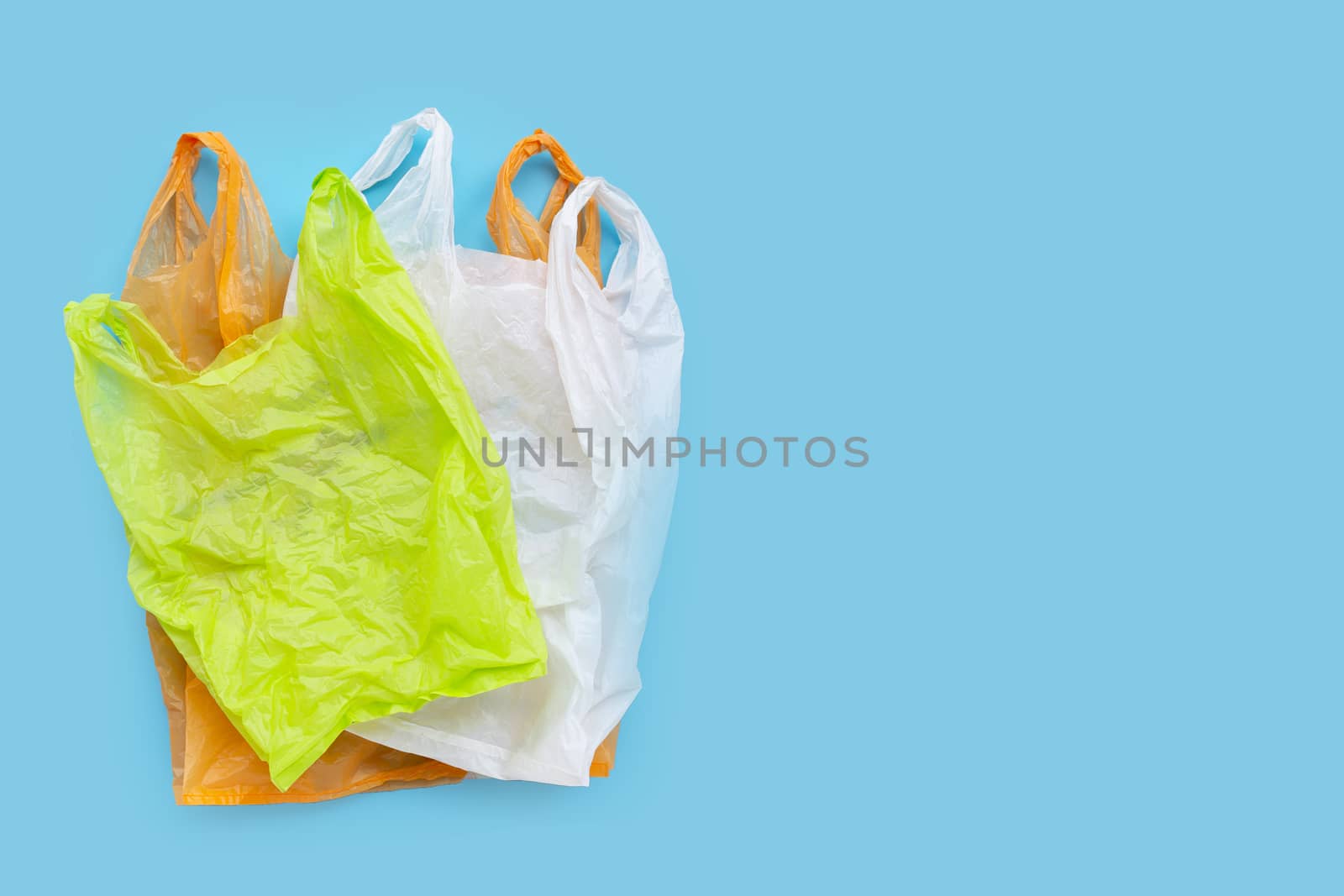 Colorful plastic bags on blue background. Copy space