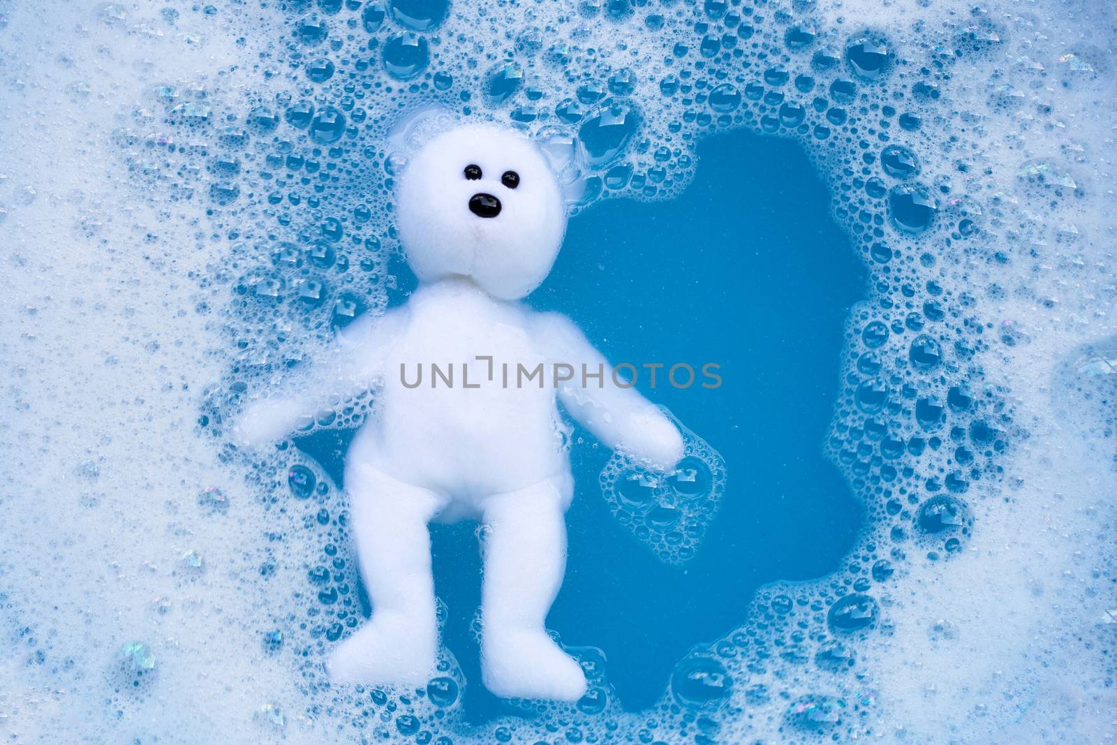 Soaking bear toy in laundry detergent water dissolution before washing. Laundry concept, Top view