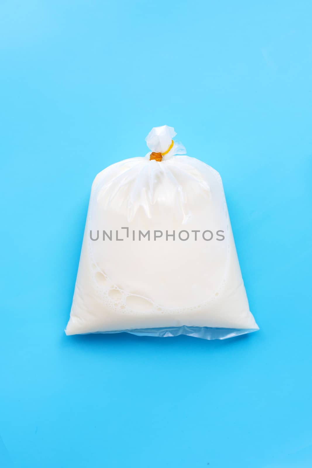 Soymilk in plastic bag on blue background. Top view