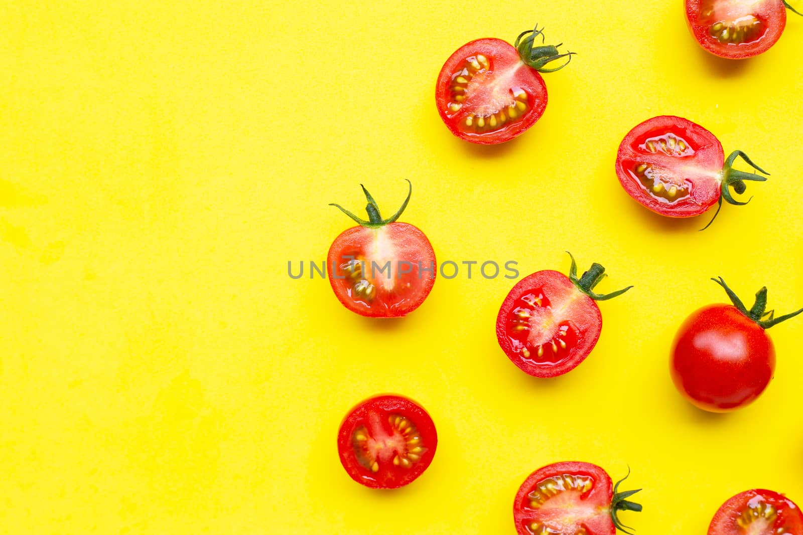 Fresh tomatoes, whole and half cut isolated on yellow background. Top view