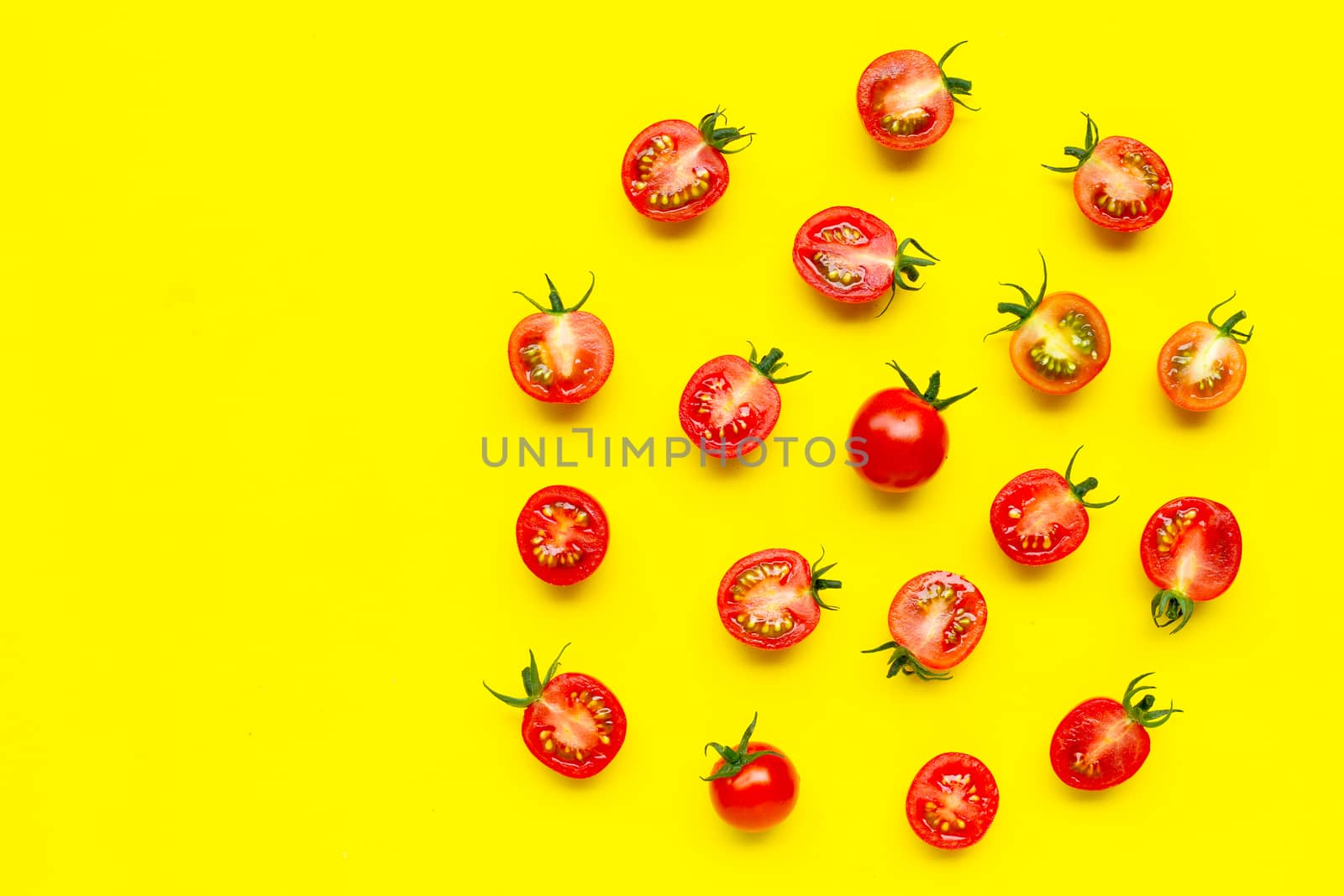 Fresh tomatoes, whole and half cut isolated on yellow background. Top view