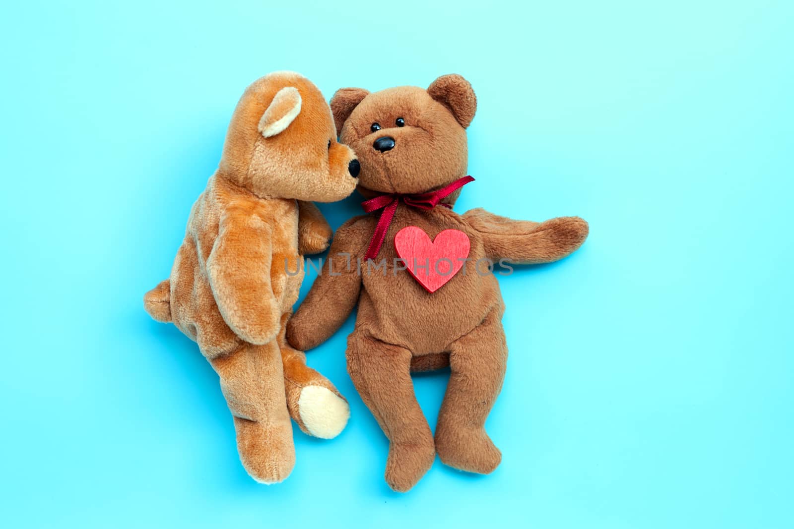 Brown bear toys kissing with red heart on blue background. Valentine's Day, Copy space