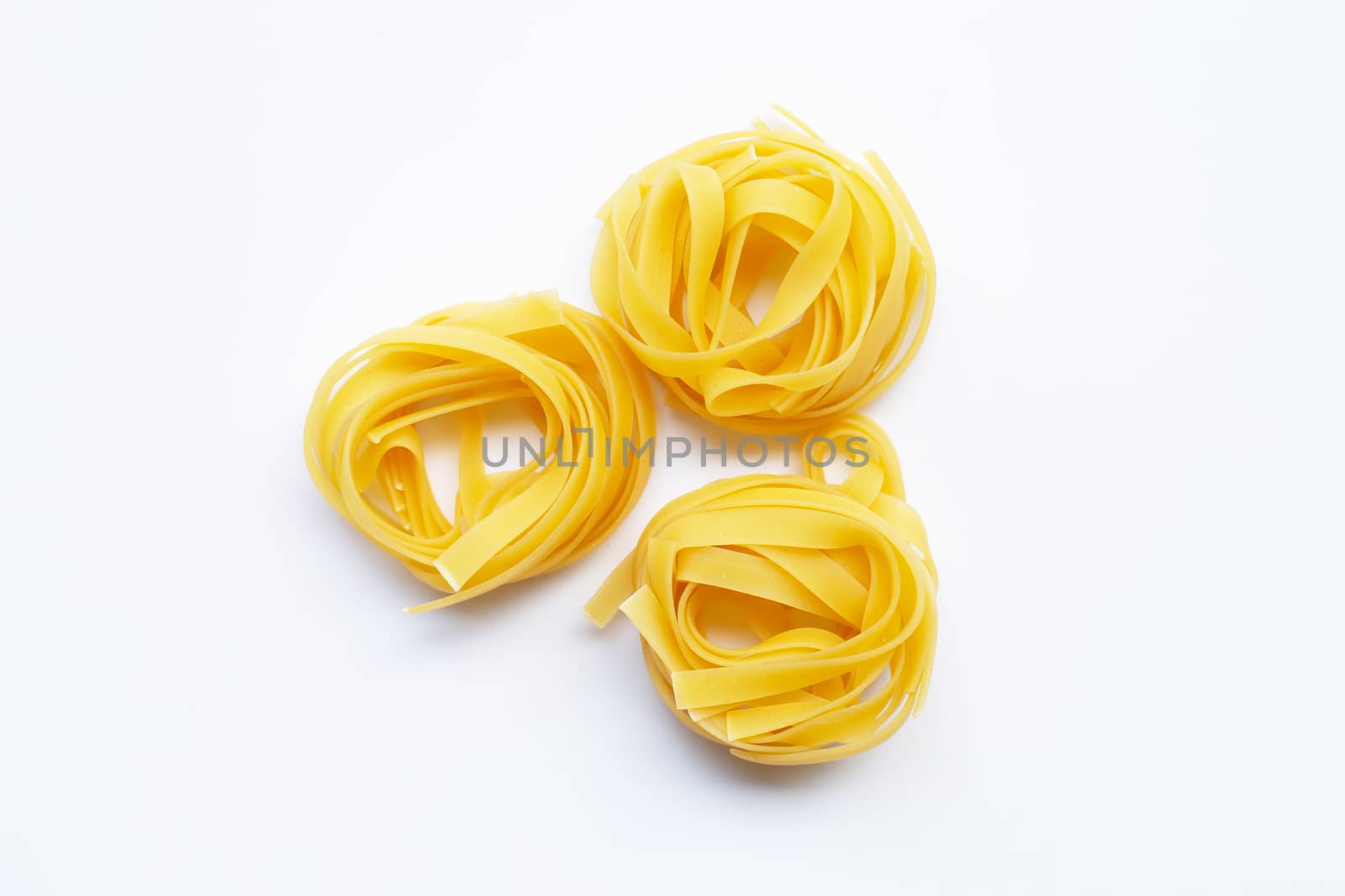 Uncooked Italian pasta tagliatelle nest on white background. Copy space