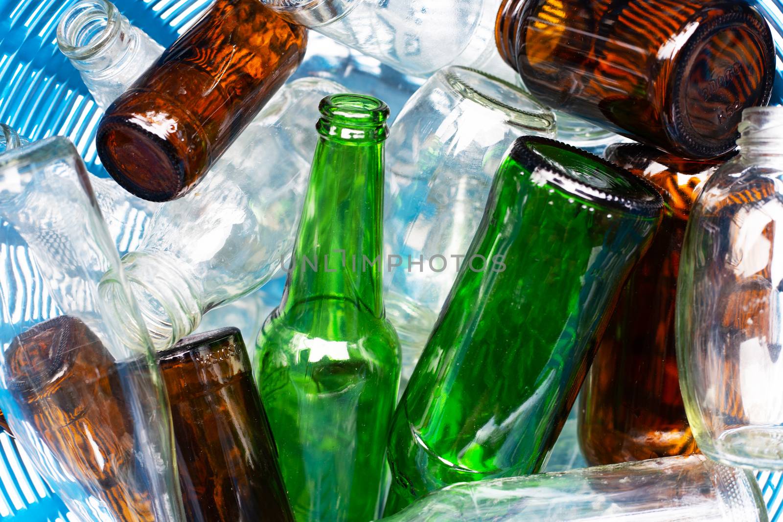 Glass bottles in blue waste basket.