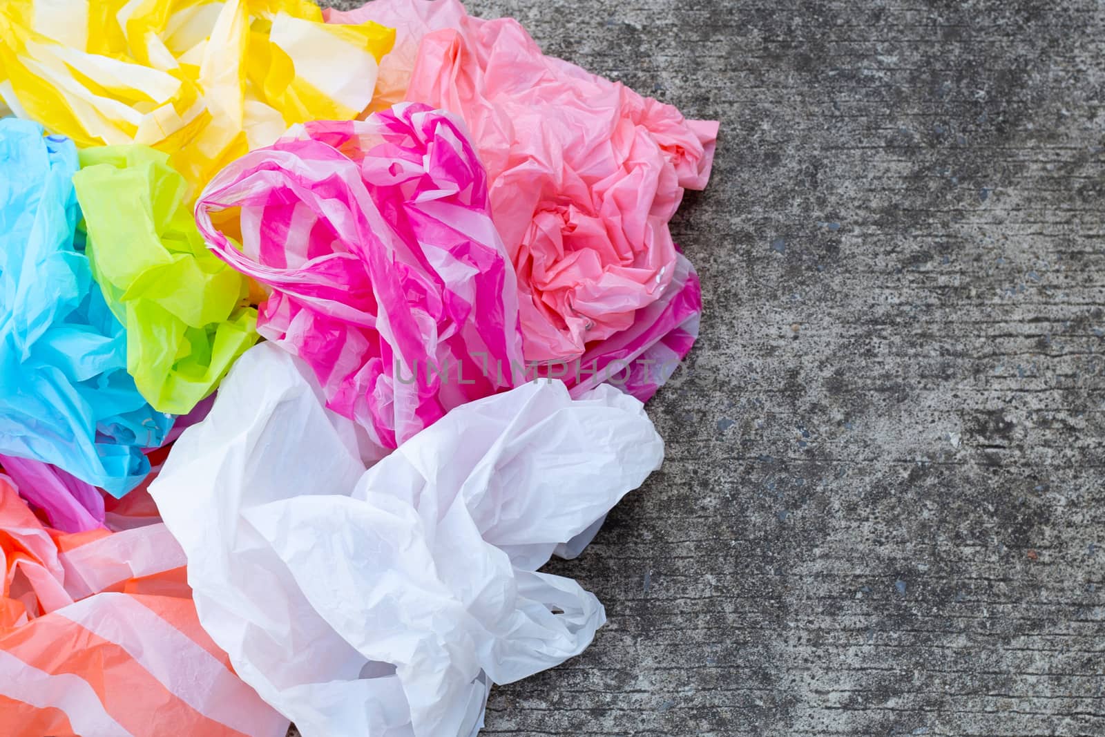 Colorful disposable plastic bags on cement floor 