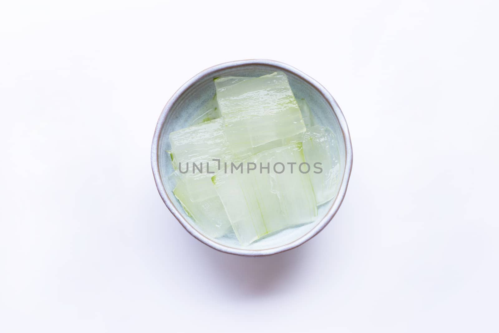 Aloe vera gel slices in ceramic bowl on white background.