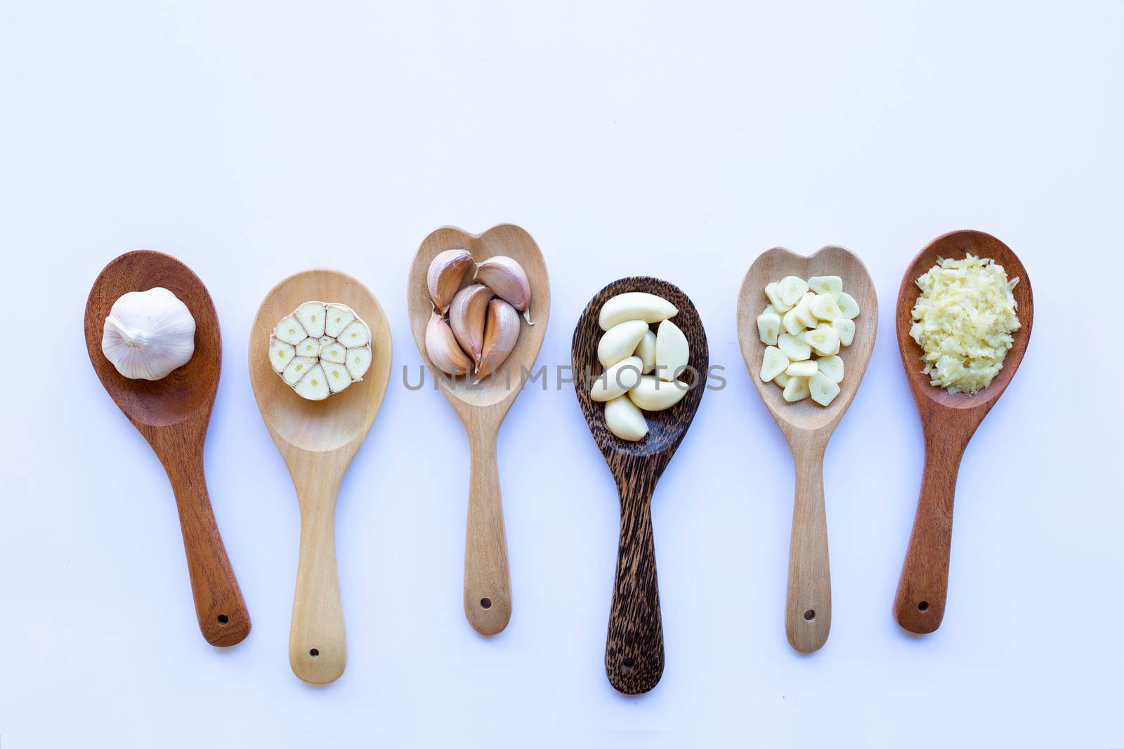 Garlic on wooden spoon on white background