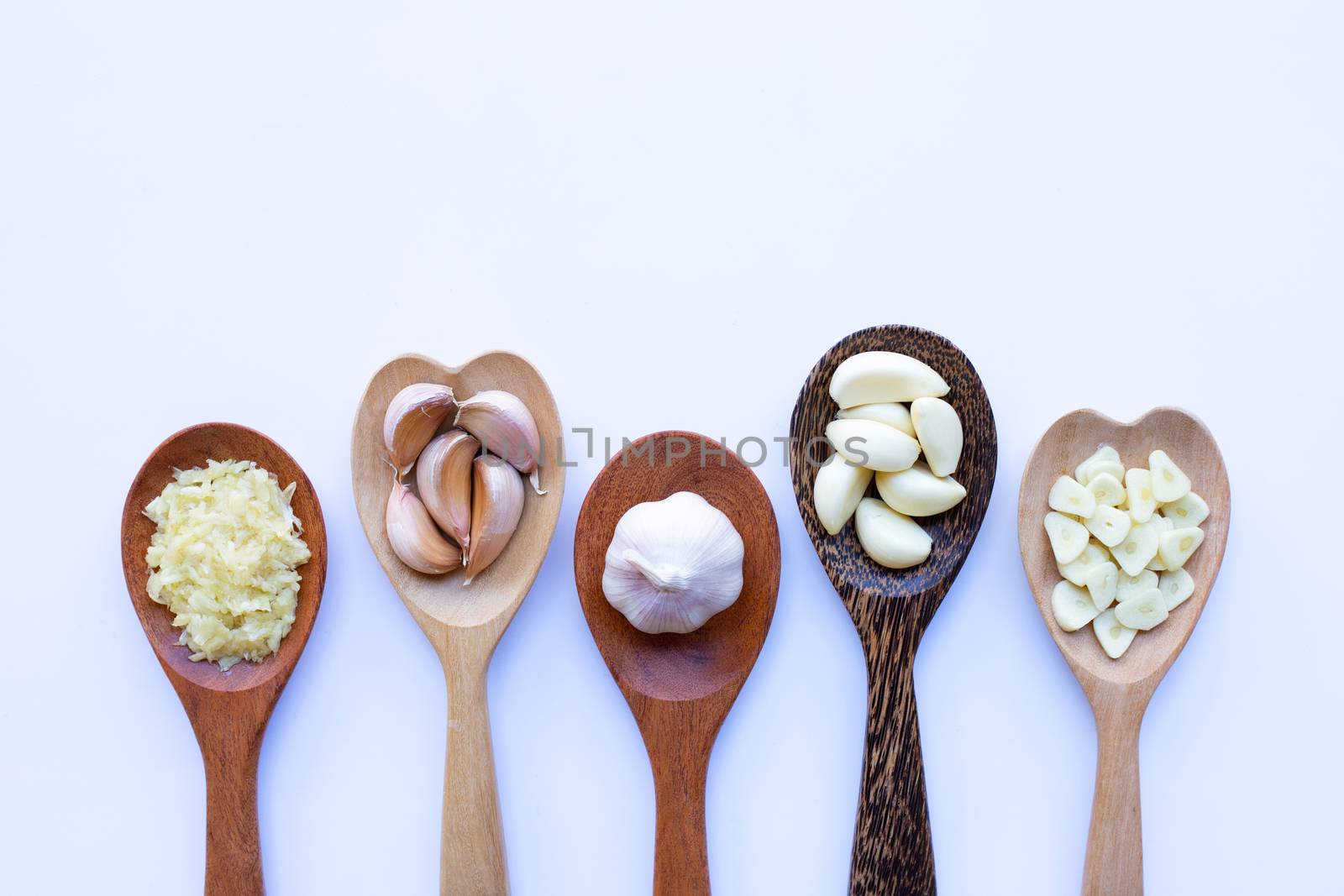 Garlic on wooden spoon on white background