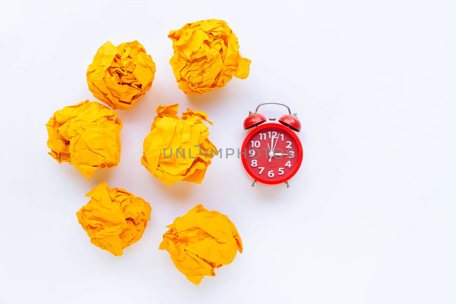Red alarm clock ring with yellow crumpled paper ball isolated on white background.
