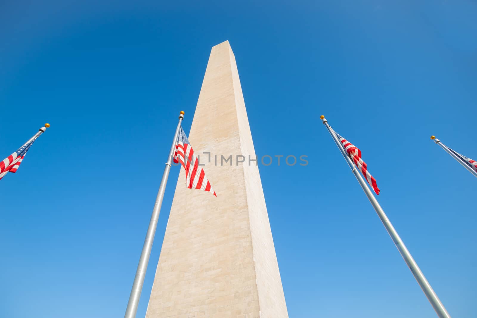 Washington Monument tall obelisk in National Mall Washington DC commemorating George Washington with flags around base.