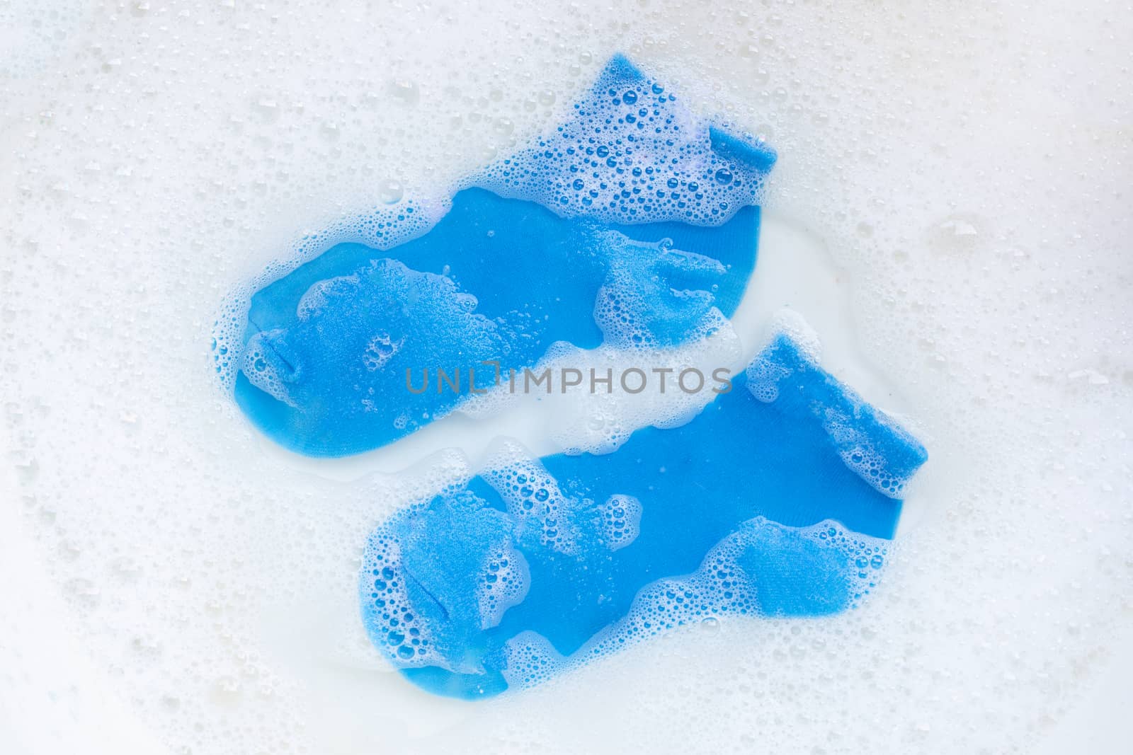 Blue socks soaking in powder detergent water dissolution. Laundry concept. Top view