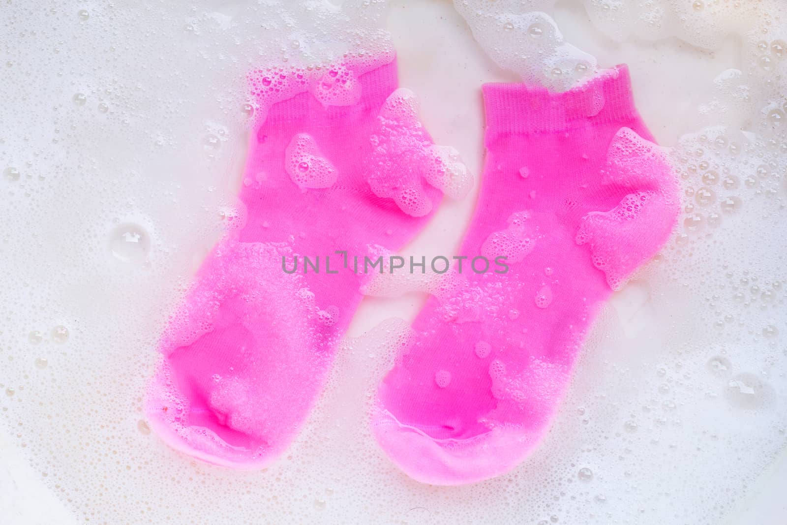 Pink  socks soaking in powder detergent water dissolution. Laundry concept. Top view