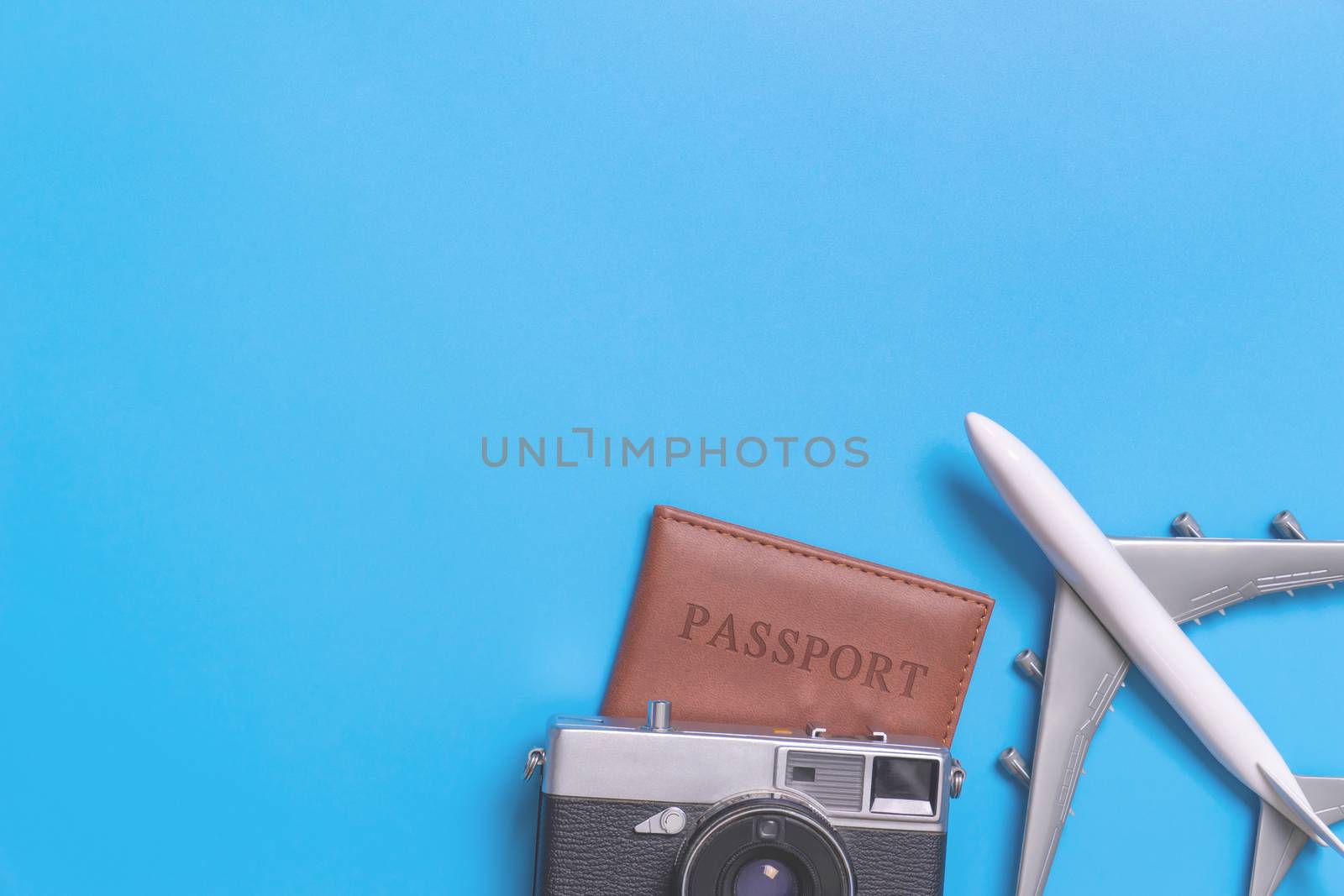 Toy plane on top of passport with vintage camera on blue copy space