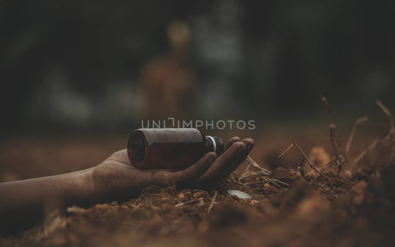 Concept of Farmer Suicide, closeup of hands with poison bottle at farm or agriculture land