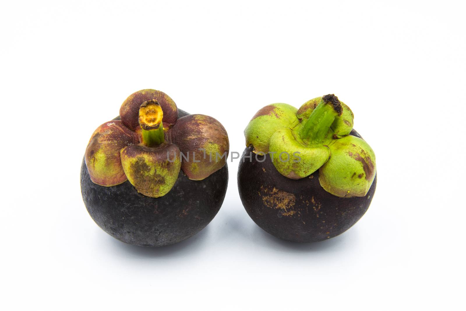 Two mangosteen placed on the white ground.