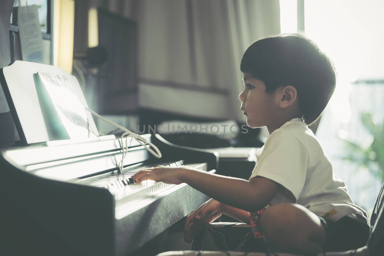 Little Boy is playing with piano and Music Tablet at home by junce