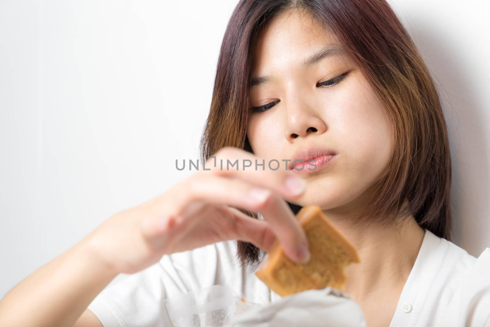 Japanese girl is enjoying the cake using her finger, on white background.