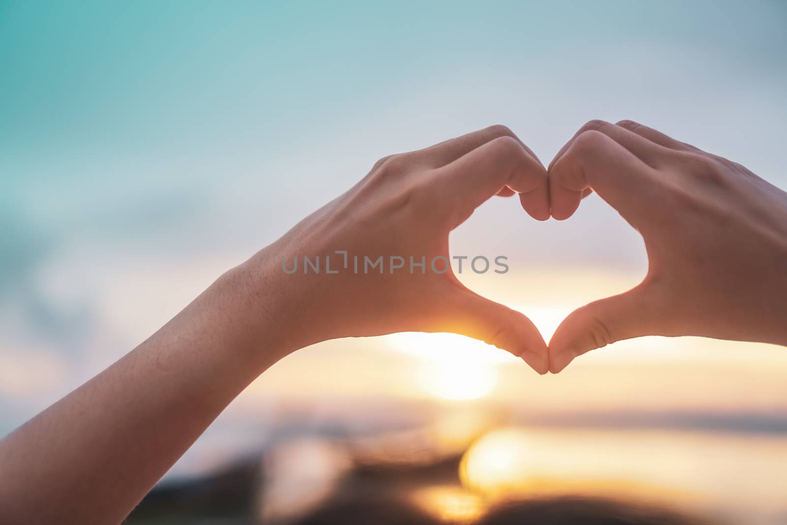 Woman hand do heart shape on blue sky  and bokeh background. by Suwant