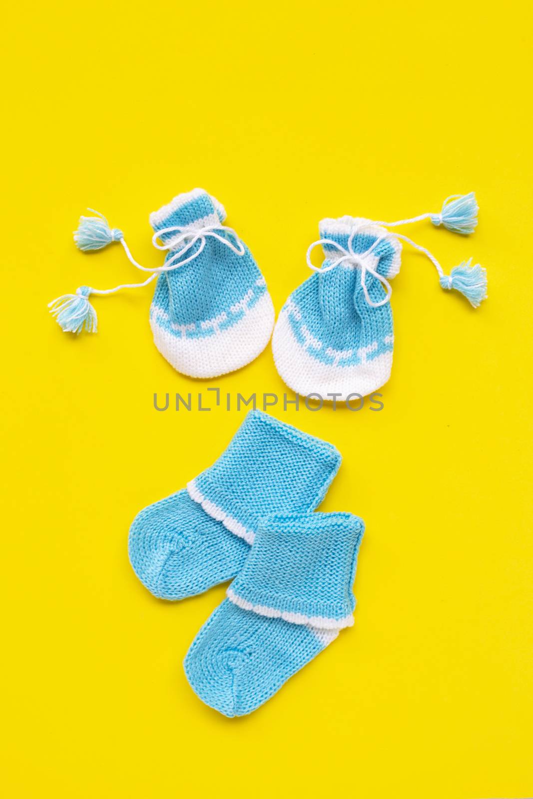 Baby gloves and socks on yellow background. by Bowonpat