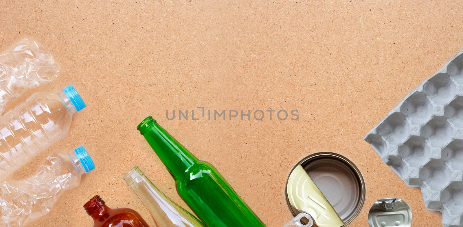 Recyclable garbage, plastic bottle, glass bottle, can and egg paper tray on brown plywood background. Copy space