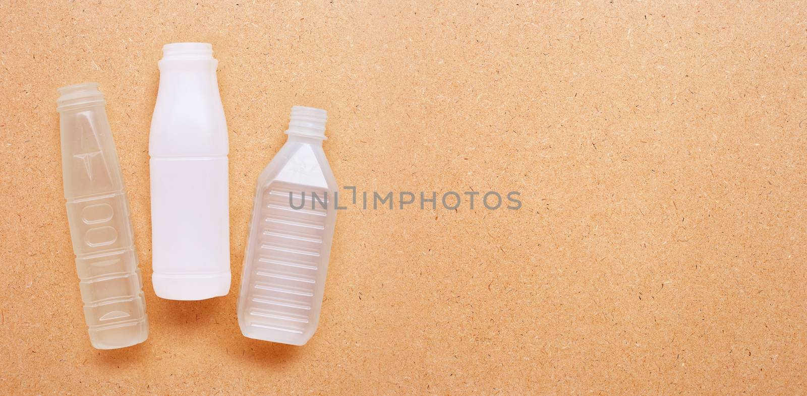 Plastic bottles on plywood background. Copy space