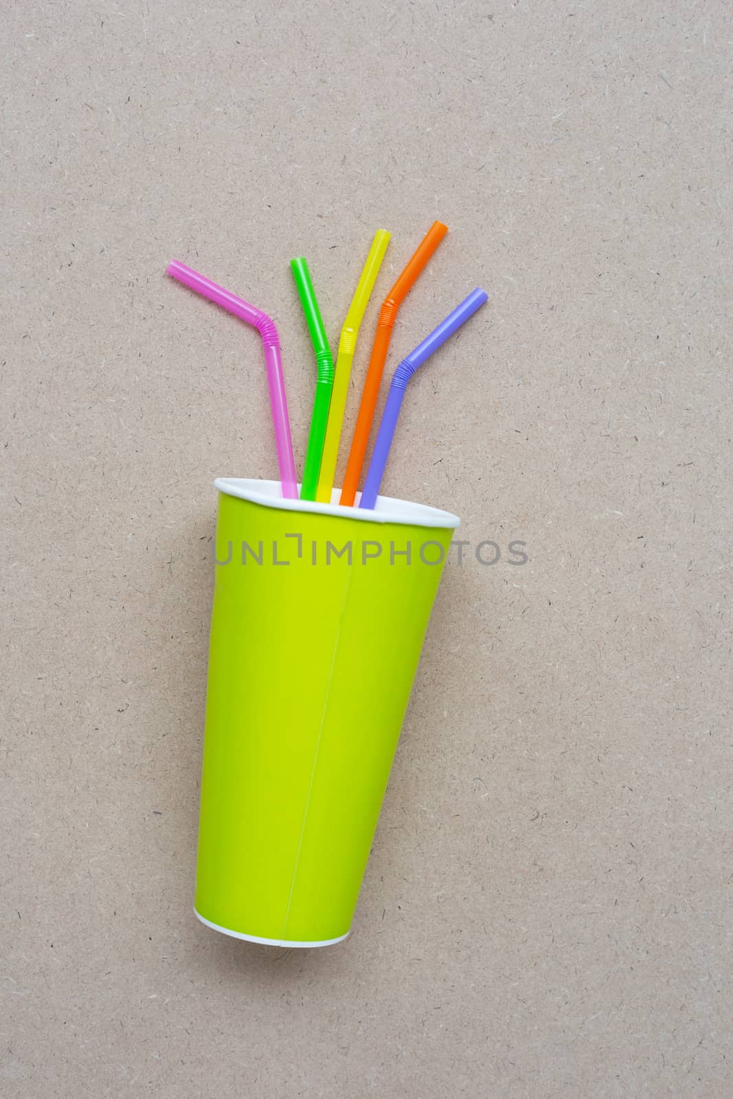 Green paper coffee cup with straws  on plywood background.