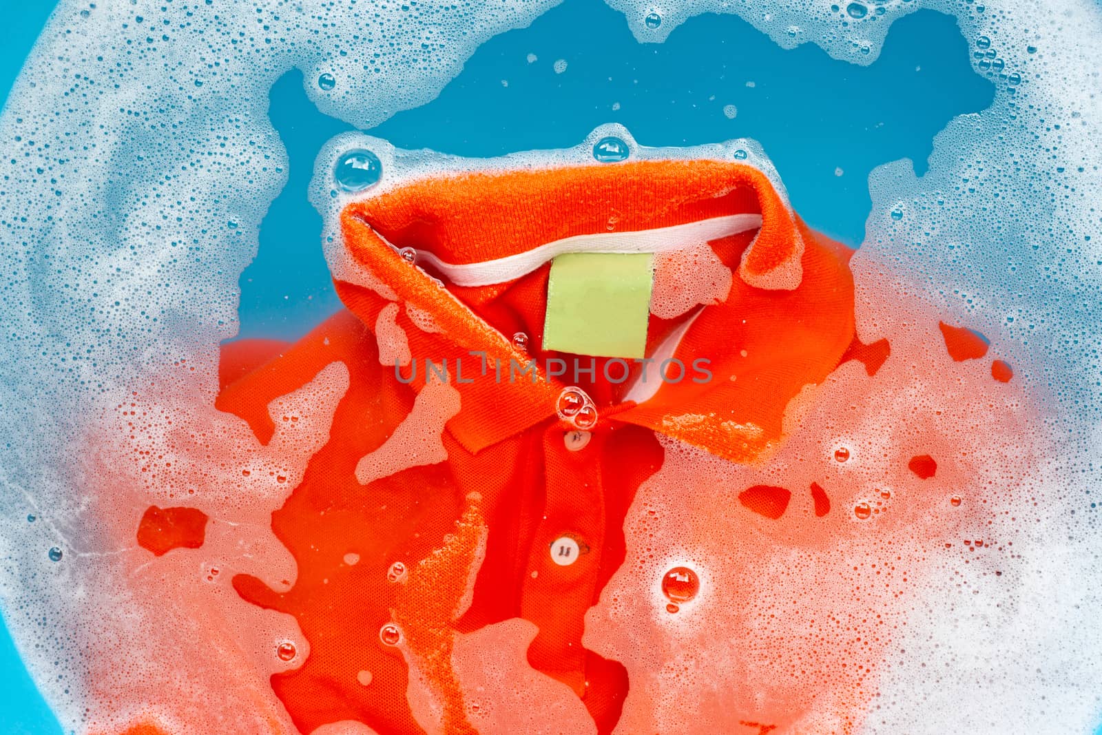 Orange polo shirt soak in powder detergent water dissolution, wa by Bowonpat