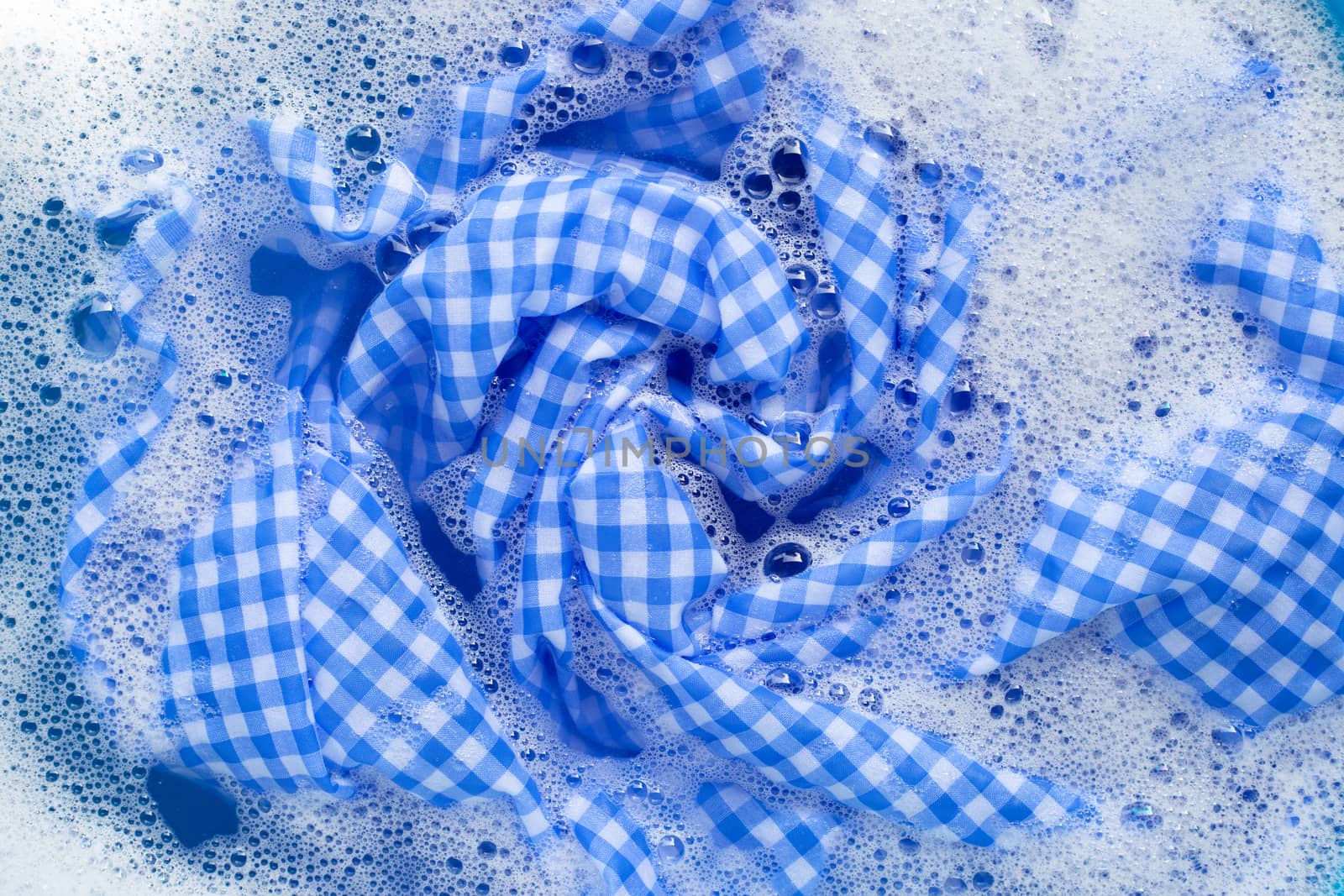 Blue white tablecloth  soak in powder detergent water dissolution, washing cloth. Laundry concept