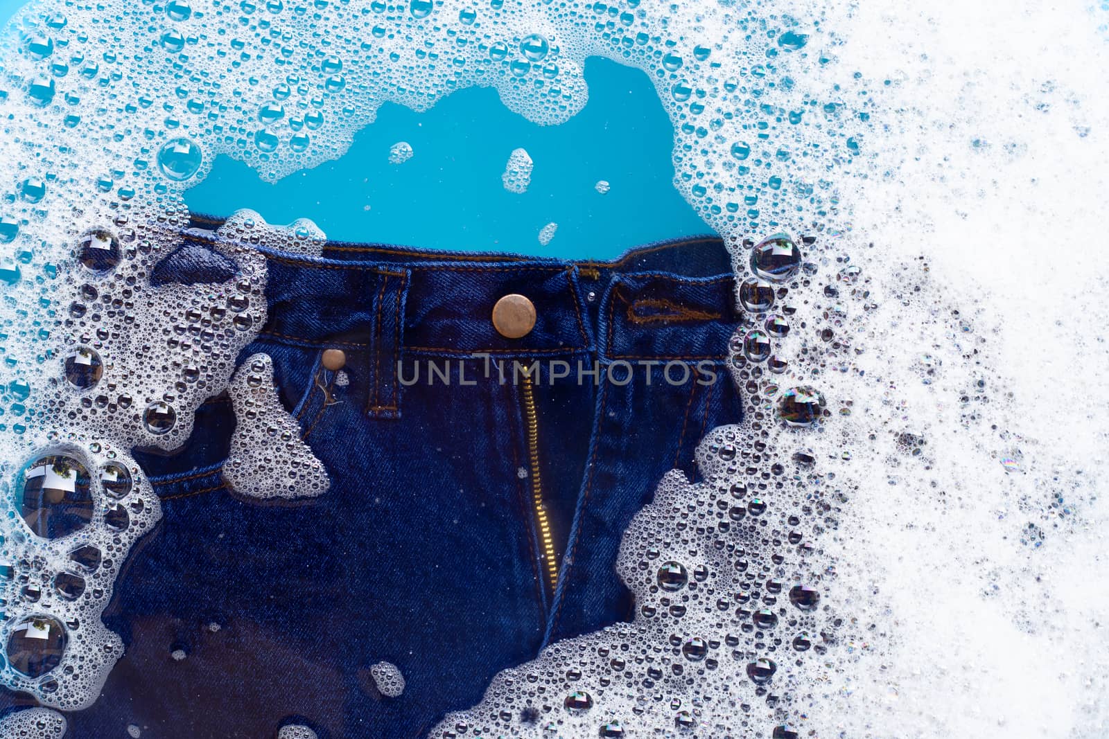 Jeans soak in powder detergent water dissolution. Laundry concep by Bowonpat