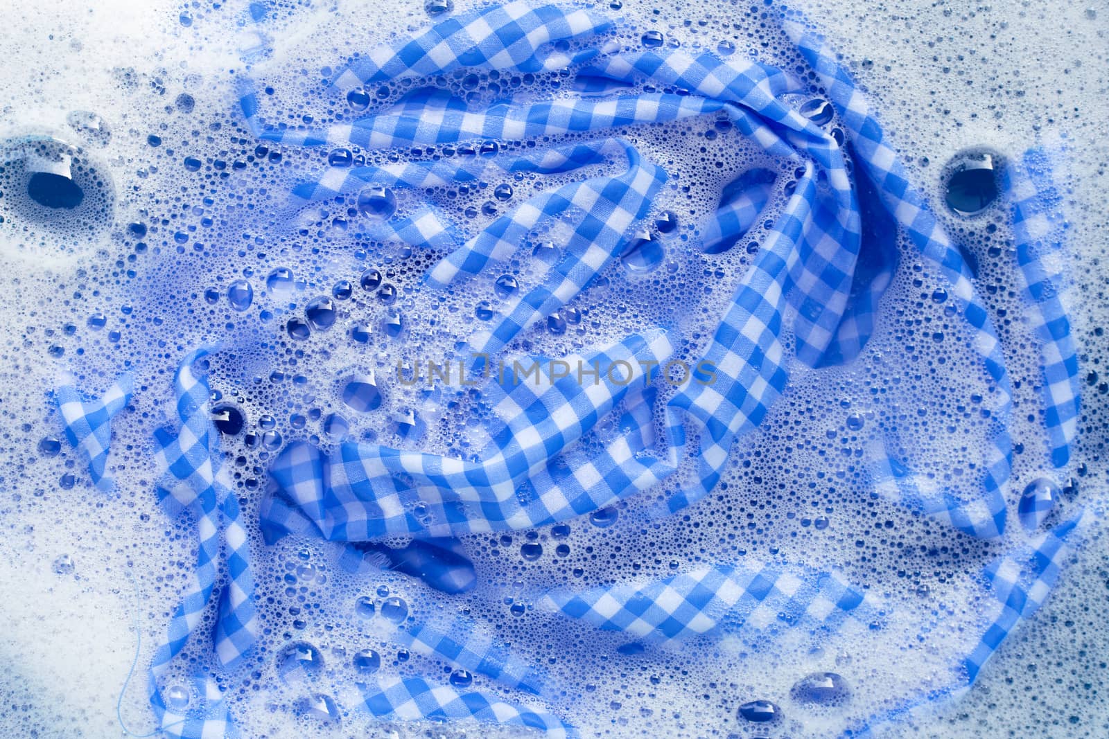 Blue white tablecloth  soak in powder detergent water dissolution, washing cloth. Laundry concept