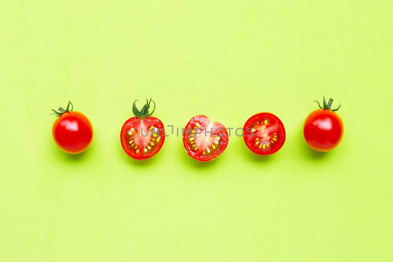Fresh  cherry tomatoes, whole and half cut on green background.  by Bowonpat