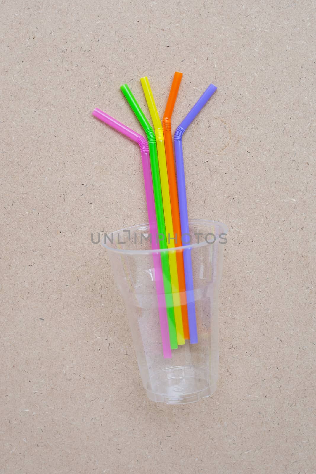 Plastic glass with straws on plywood background.