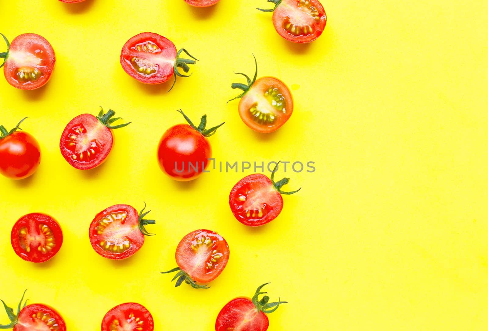 Fresh cherry tomatoes, whole and half cut isolated on yellow bac by Bowonpat