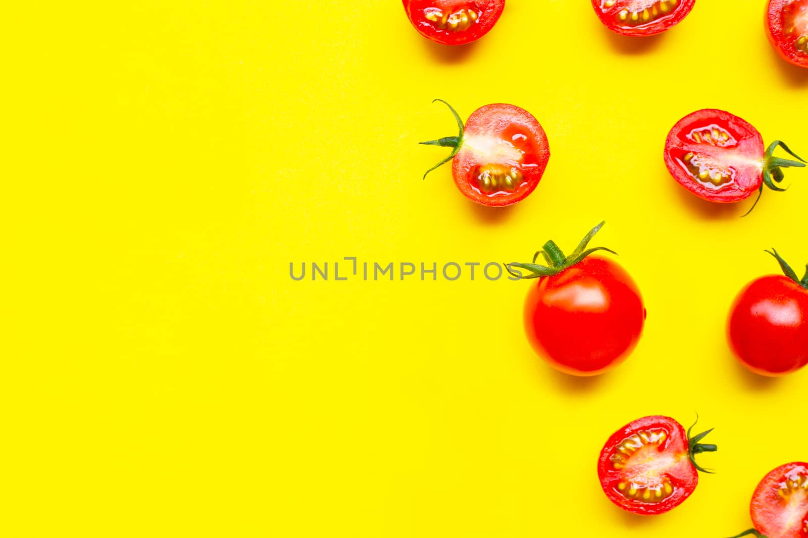 Fresh cherry tomatoes, whole and half cut isolated on yellow bac by Bowonpat