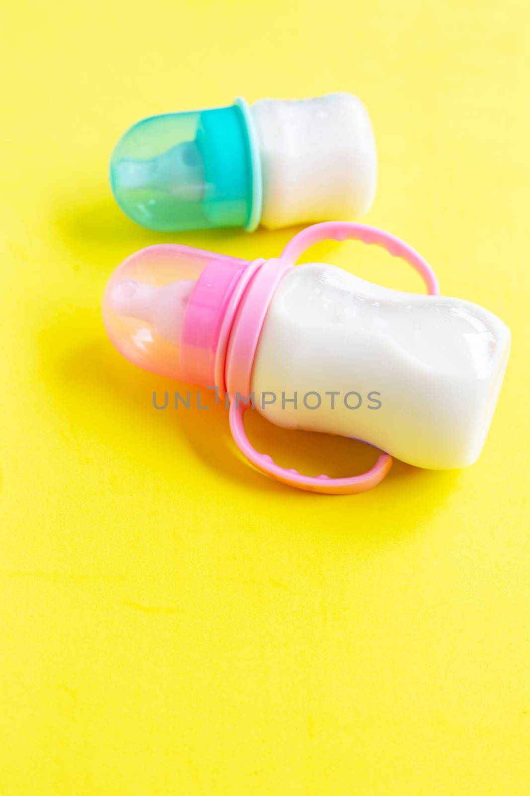 Bottles of milk for baby on yellow background.  Copy space